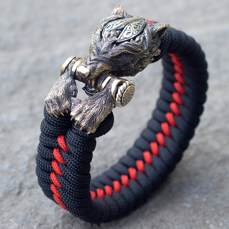 Warrior Wolf bracelet close-up showing the sculpted wolf head, paw details, crossbar, and black-and-red braid